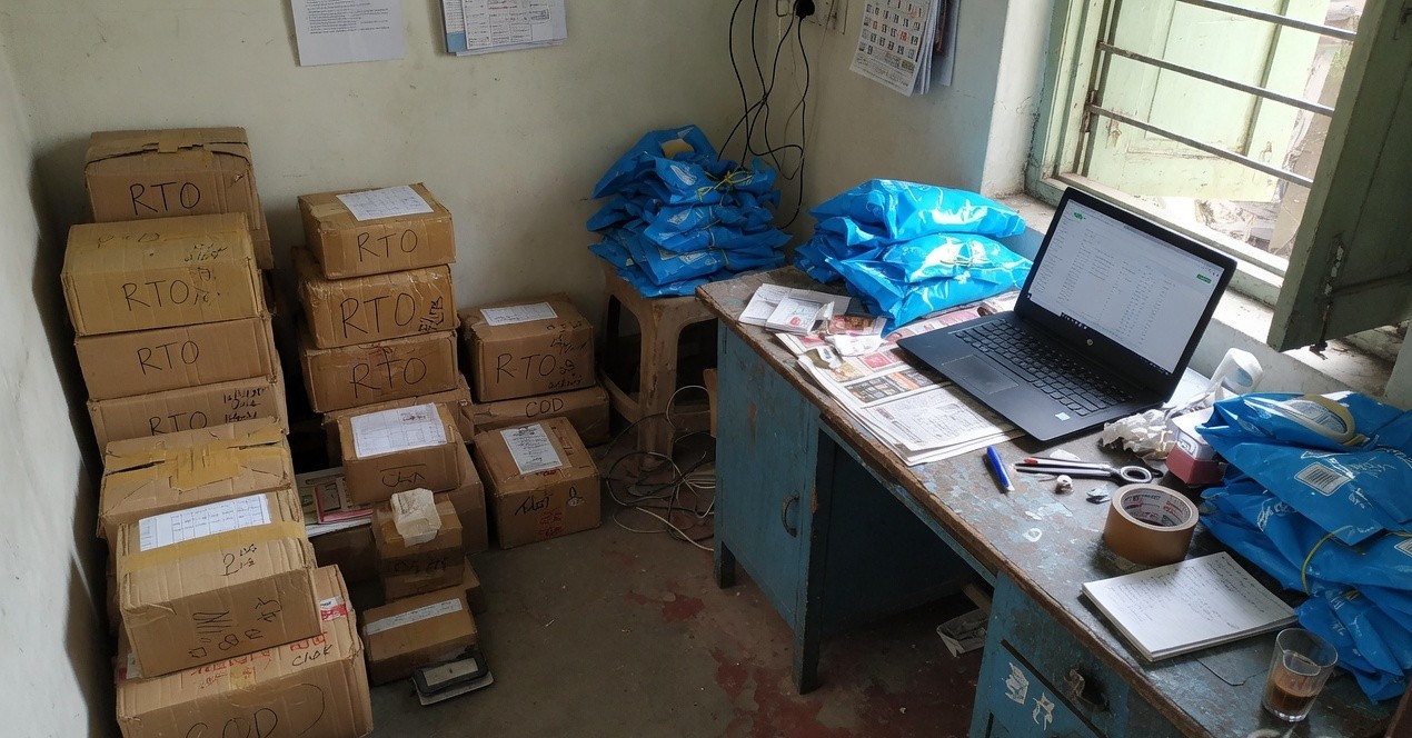 Stacks of COD and RTO cardboard courier parcels in a small Indian ecommerce workspace